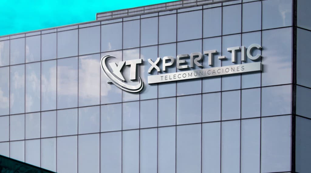 Logo Xpert-Tic en fachada de vidrio de edificio corporativo, acabado metálico tridimensional